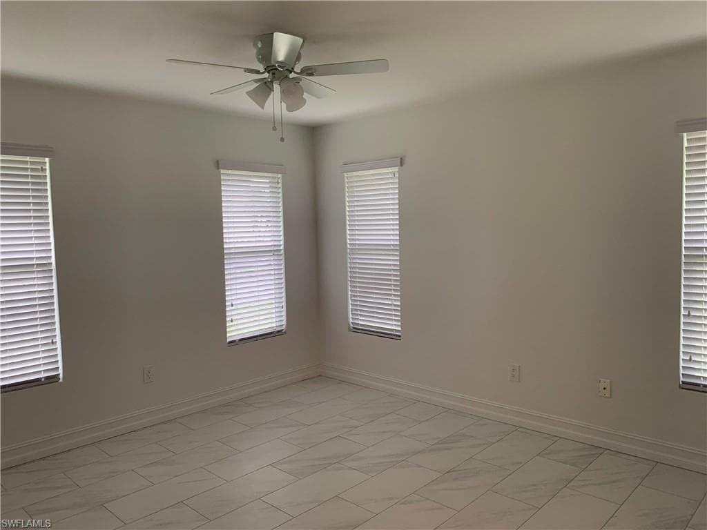 Unfurnished room with a ceiling fan baseboards