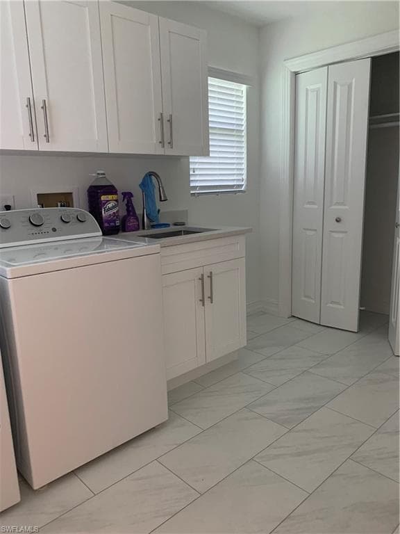 Laundry area featuring washer/dryer extra storage and light marble finish flooring