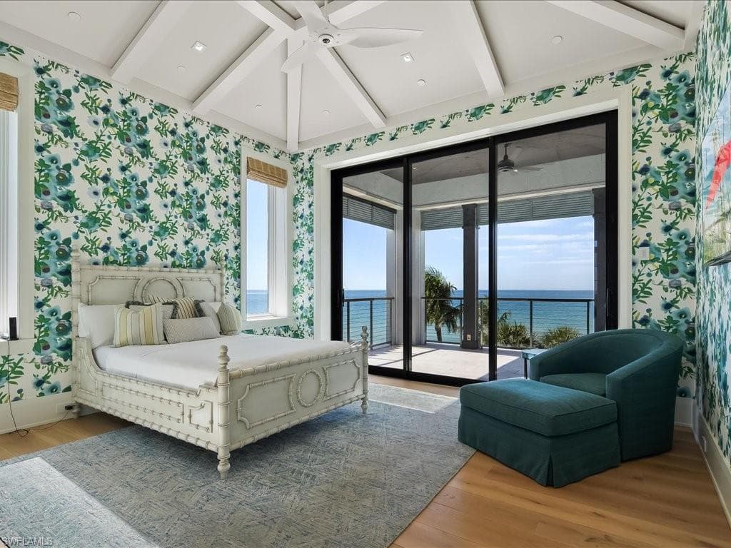 Bedroom with wallpapered walls, beam ceiling, access to exterior, light wood-style flooring, and a ceiling fan