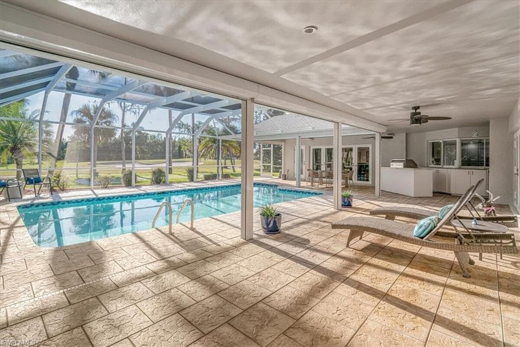 Swimming pool featuring a patio, ceiling fan, a sunroom, a lanai, and exterior kitchen
