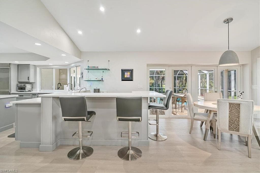 Kitchen with recessed lighting, lofted ceiling, decorative light fixtures, a kitchen breakfast bar, and gray cabinetry