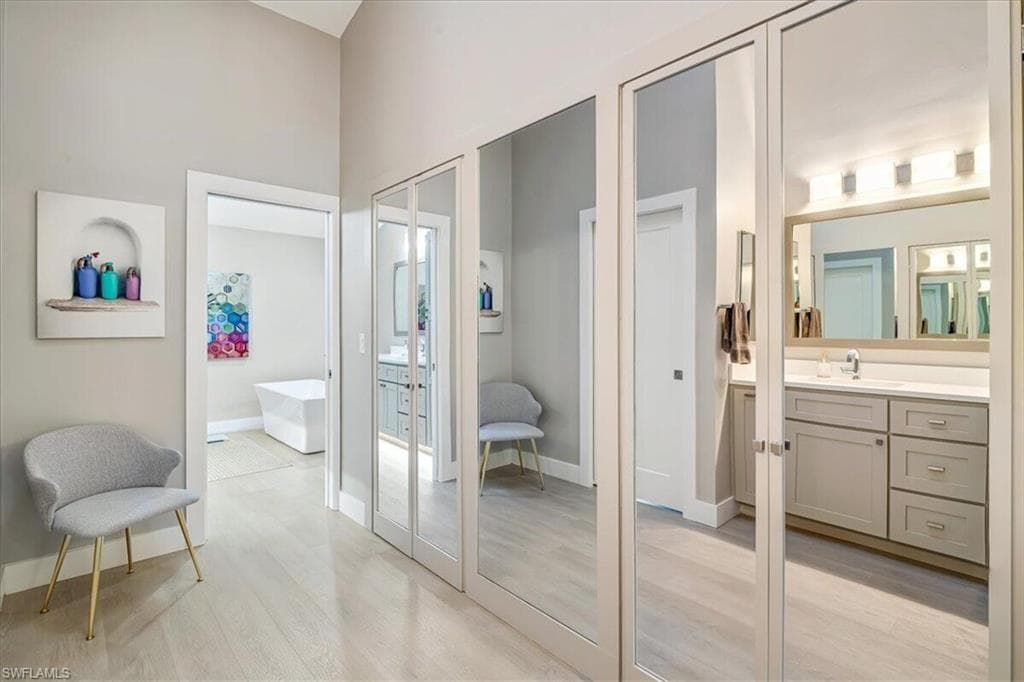 Full bath featuring light wood finished floors, vanity, and a freestanding tub