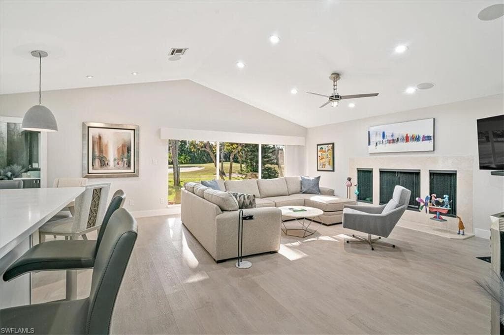 Living room with vaulted ceiling, light wood finished floors, recessed lighting, and a ceiling fan