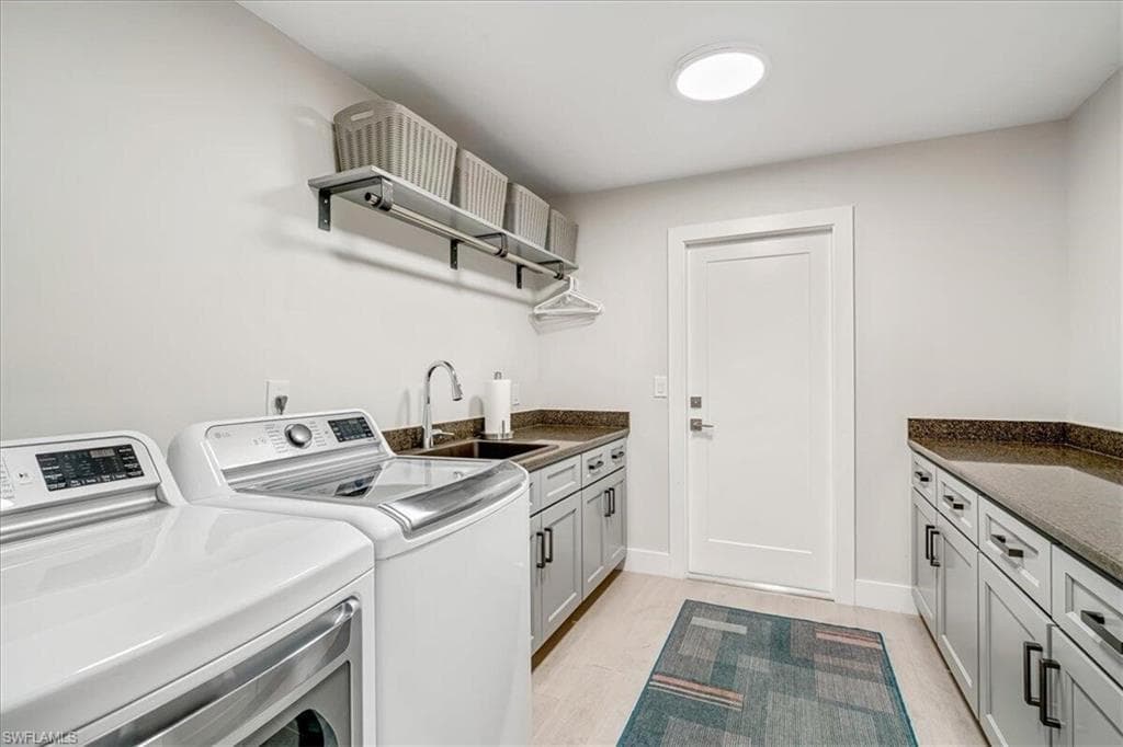 Laundry area with cabinet space, washing machine and clothes dryer, and light wood-type flooring
