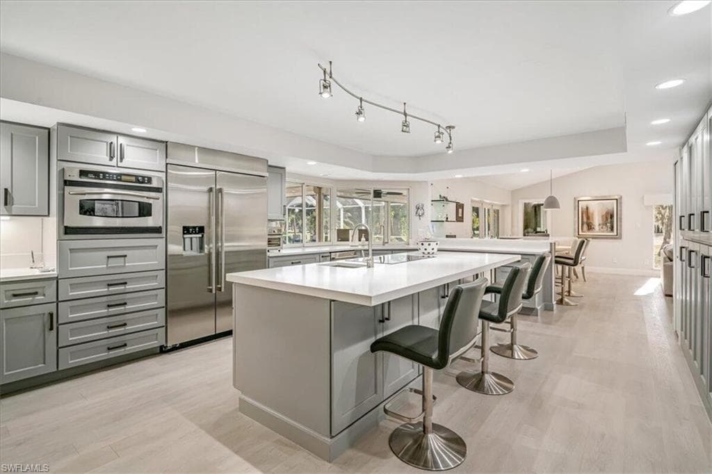 Kitchen featuring gray cabinets, recessed lighting, a breakfast bar, appliances with stainless steel finishes, and light wood-style flooring
