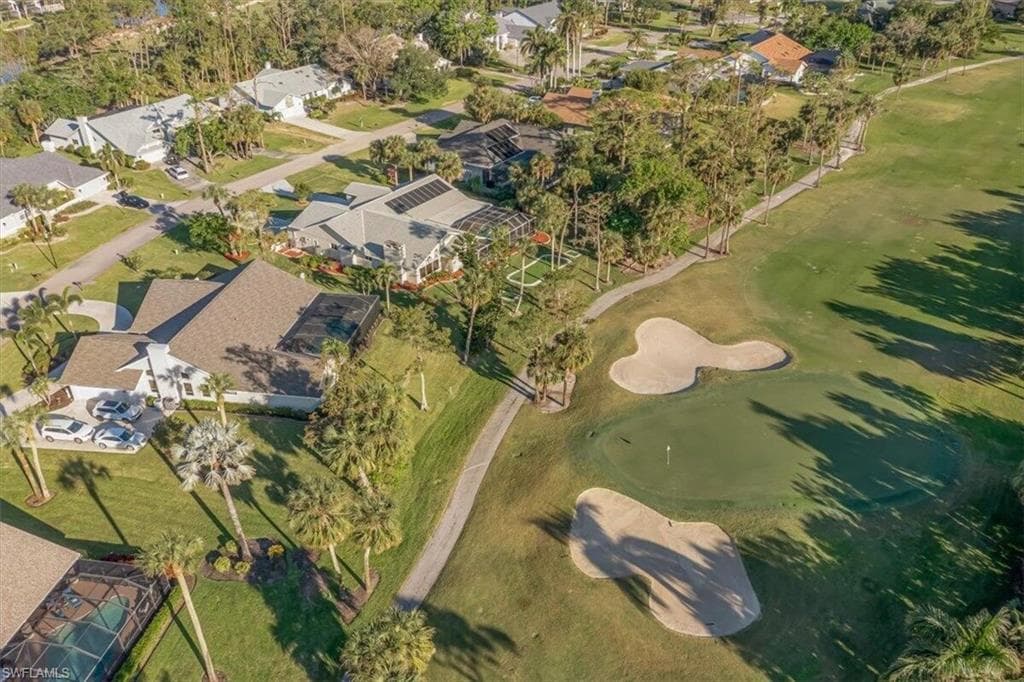 Aerial view of property and surrounding area featuring a golf course and nearby suburban area