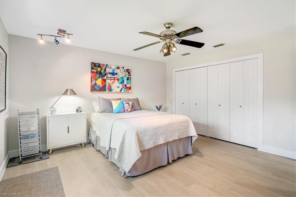 Bedroom featuring light wood-style floors, ceiling fan, and a closet