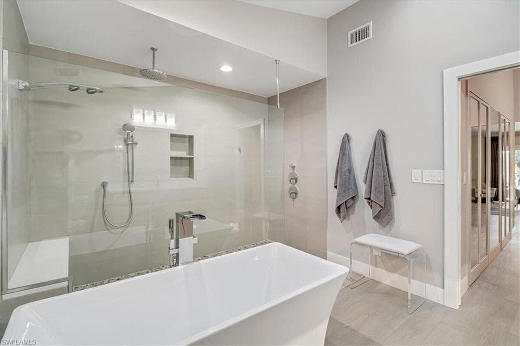 Bathroom featuring a freestanding bath, a stall shower, recessed lighting, and wood finished floors