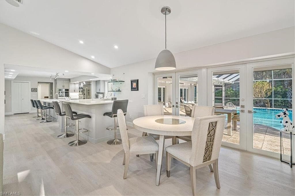 Dining room with light wood-style floors, vaulted ceiling, french doors, and recessed lighting