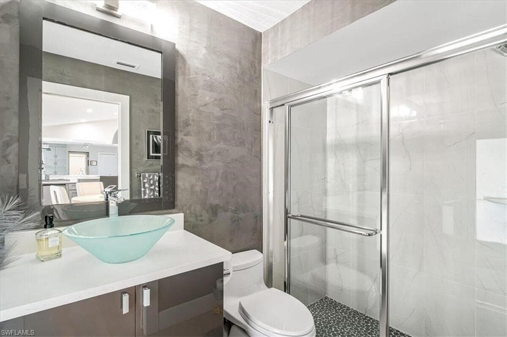 Bathroom featuring vanity and a marble finish shower