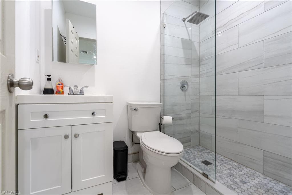 Full bath featuring vanity, tiled shower, and light tile patterned floors
