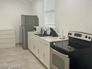 Kitchen with a breakfast bar area, appliances with stainless steel finishes, tasteful backsplash, open floor plan, and white cabinetry