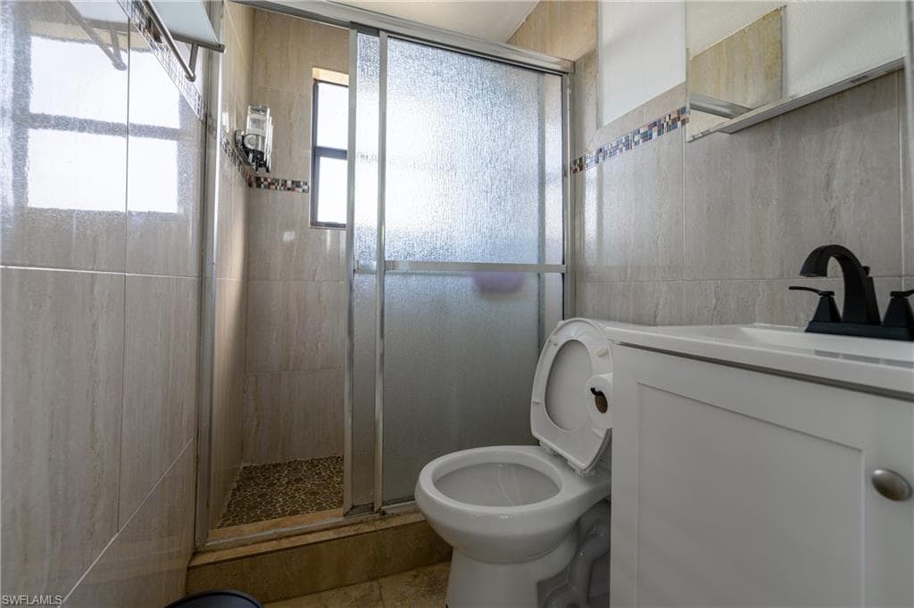Full bathroom featuring vanity, a stall shower, and tile walls