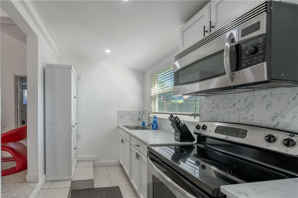 Kitchen with stainless steel appliances, white cabinets, tasteful backsplash, light tile patterned floors, and recessed lighting