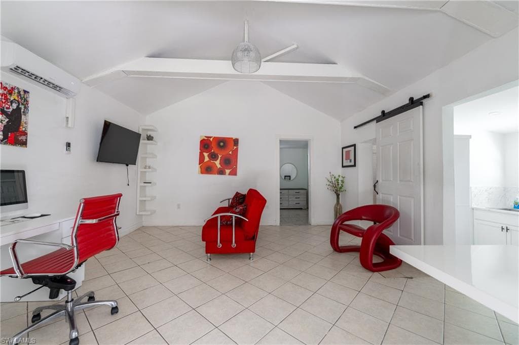 Office area featuring a barn door, a wall mounted AC, light tile patterned floors, and a ceiling fan