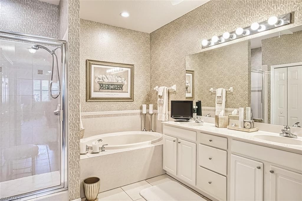 Bathroom with wallpapered walls, double vanity, light tile patterned floors, a shower stall, and a bath