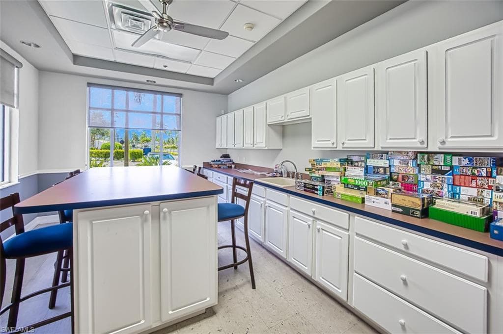 Kitchen with a breakfast bar, dark countertops, and white cabinets