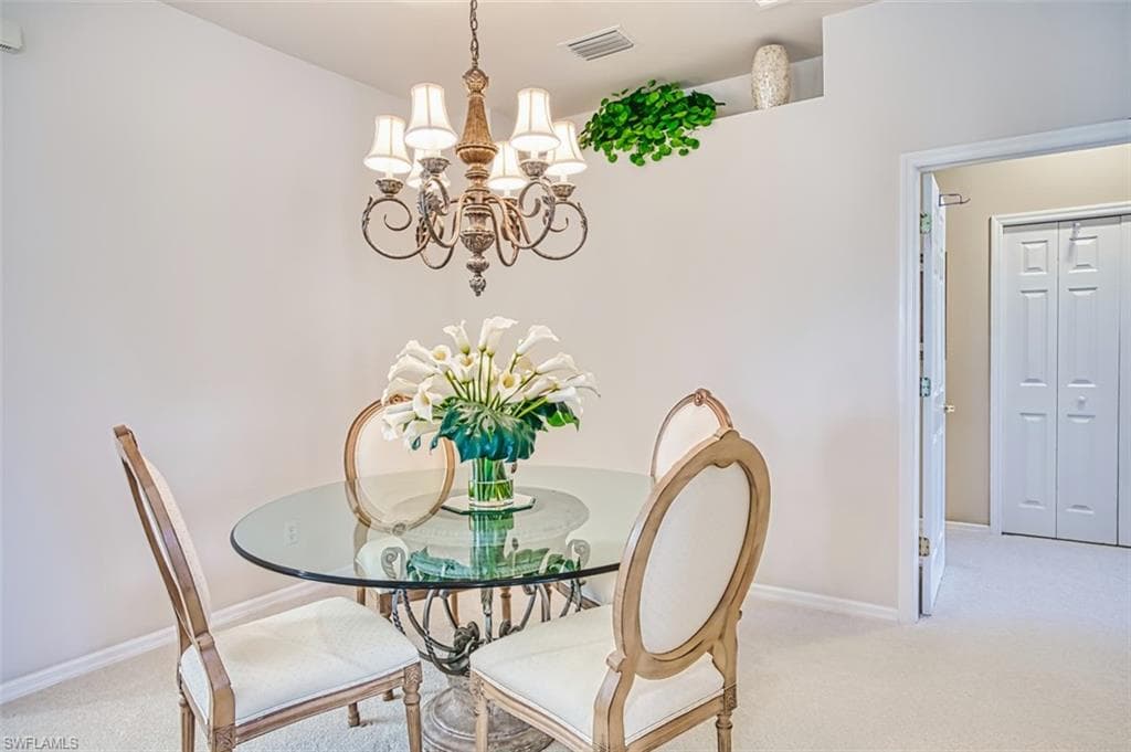 Dining area with light carpet and a chandelier