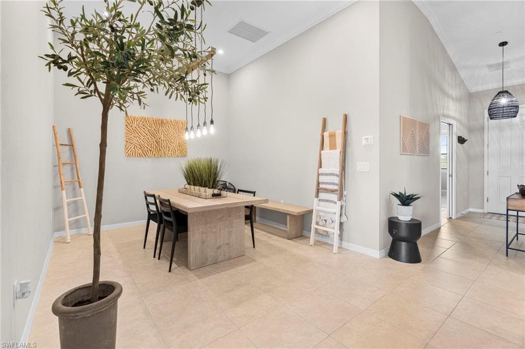 Dining room with crown molding, light tile patterned floors, and a high ceiling