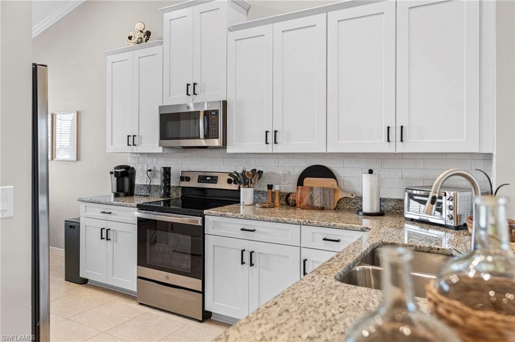 Kitchen featuring appliances with stainless steel finishes, white cabinets, and backsplash