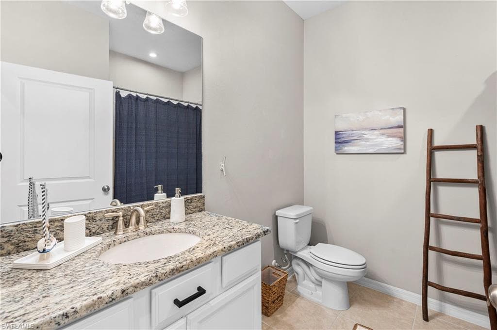 Bathroom with a shower with curtain, light tile patterned floors, and vanity
