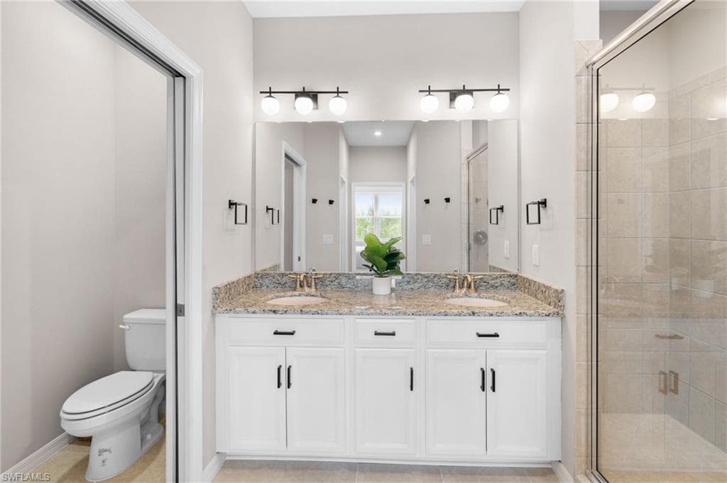 Full bath with double vanity, a stall shower, and light tile patterned floors