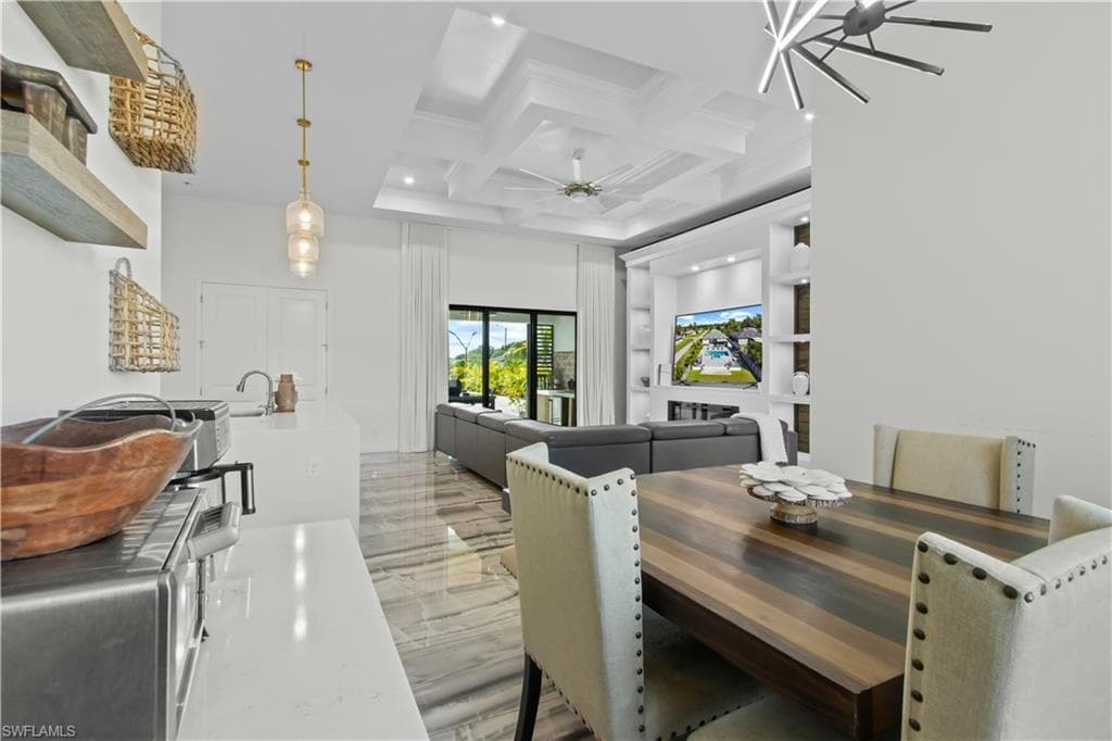 Dining space with coffered ceiling, beam ceiling, and a ceiling fan