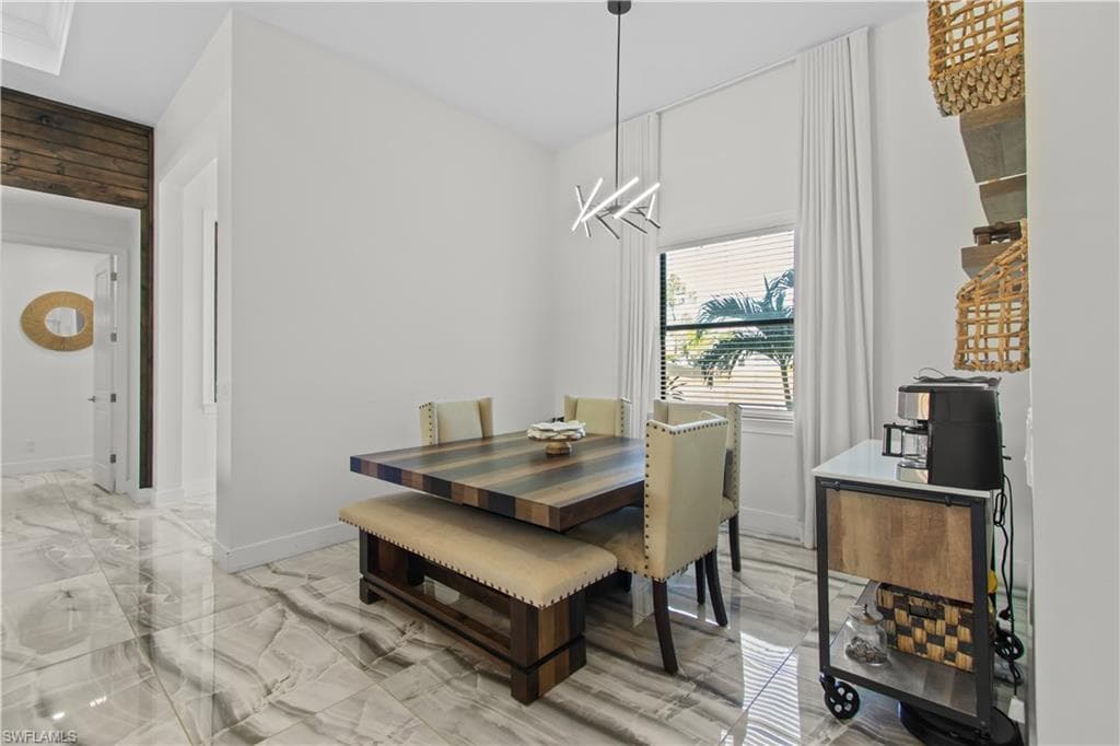 Dining space featuring light marble finish flooring and a chandelier