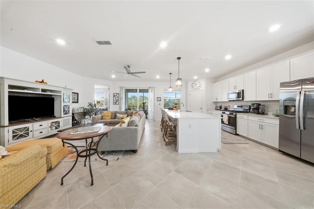 Kitchen with open floor plan, appliances with stainless steel finishes, decorative light fixtures, a kitchen island with sink, and recessed lighting