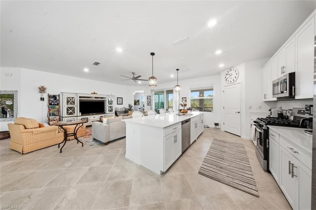 Kitchen featuring white cabinetry, appliances with stainless steel finishes, open floor plan, hanging light fixtures, and recessed lighting