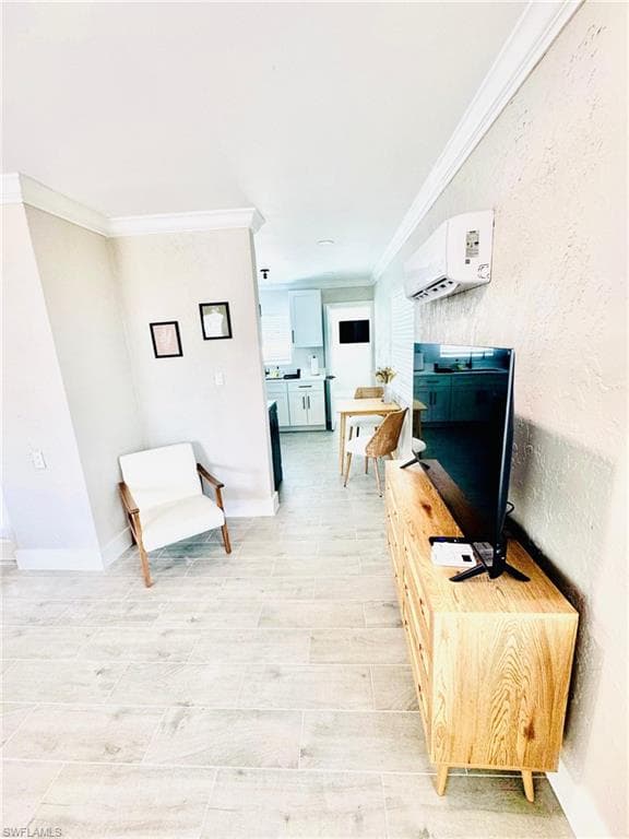 Living area with ornamental molding, a wall mounted air conditioner, and a textured wall