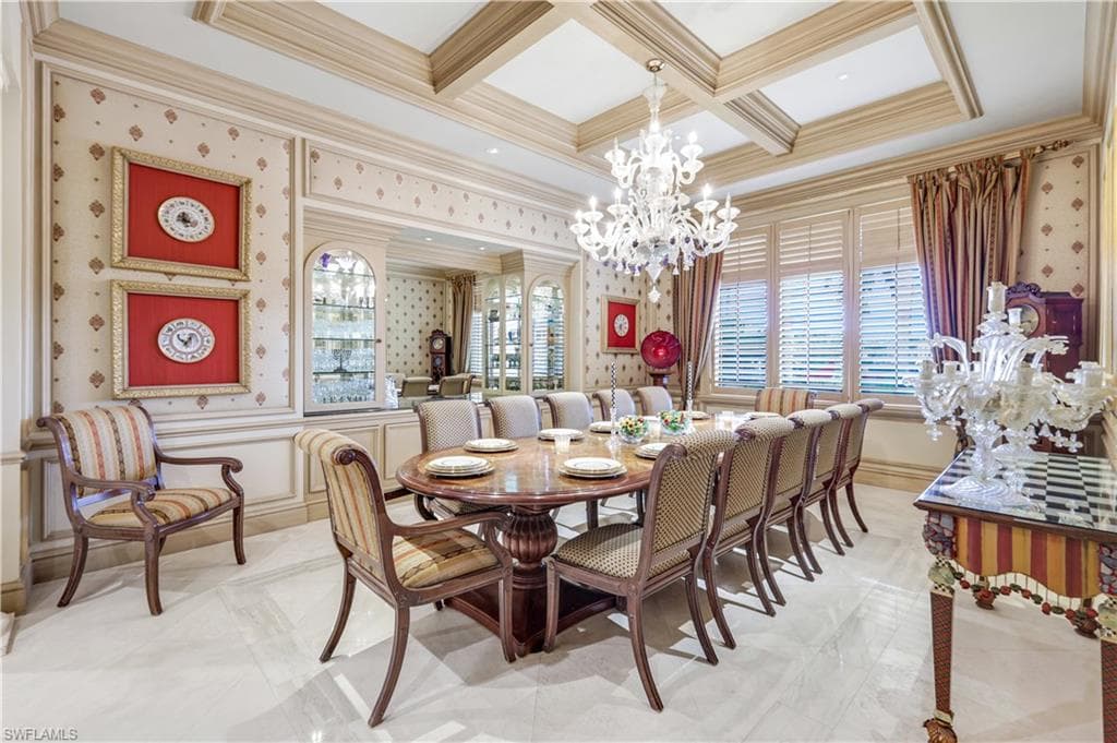 Dining space with wallpapered walls, crown molding, a chandelier, coffered ceiling, and beamed ceiling and wine room adjacent