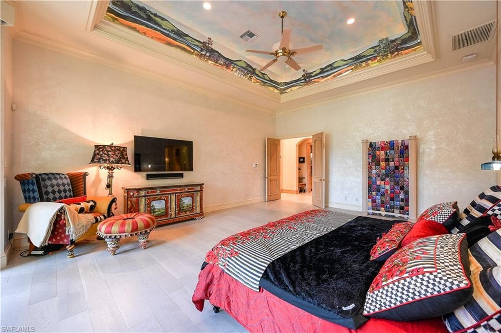 Bedroom with a tray ceiling, arched walkways, ornamental molding, and wood finished floors