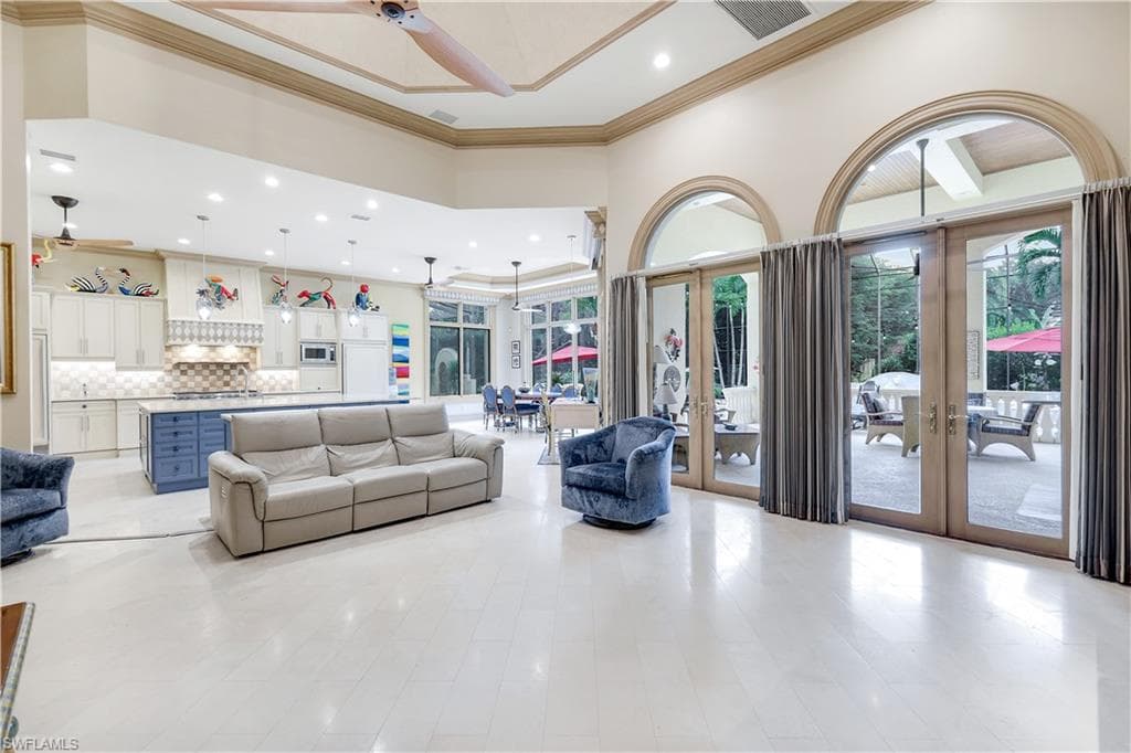 Living area featuring french doors, a towering ceiling, ceiling fan, ornamental molding, and recessed lighting