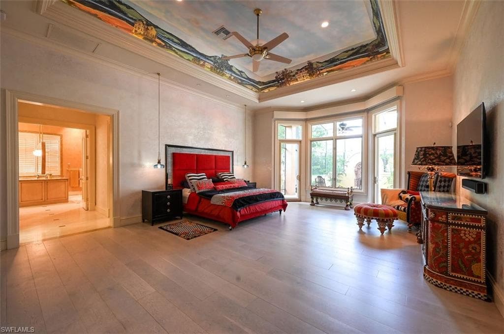 Bedroom featuring a tray ceiling, hardwood / wood-style flooring, recessed lighting, ornamental molding, and a ceiling fan