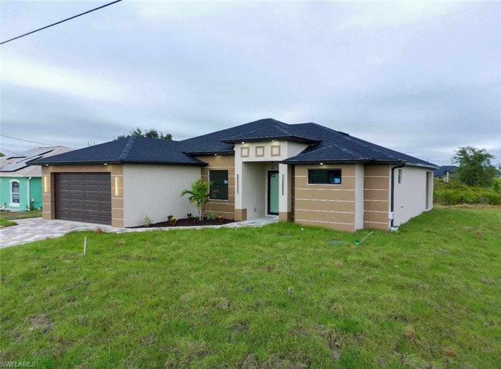 Prairie-style home with stucco siding, a front lawn, a garage, and driveway