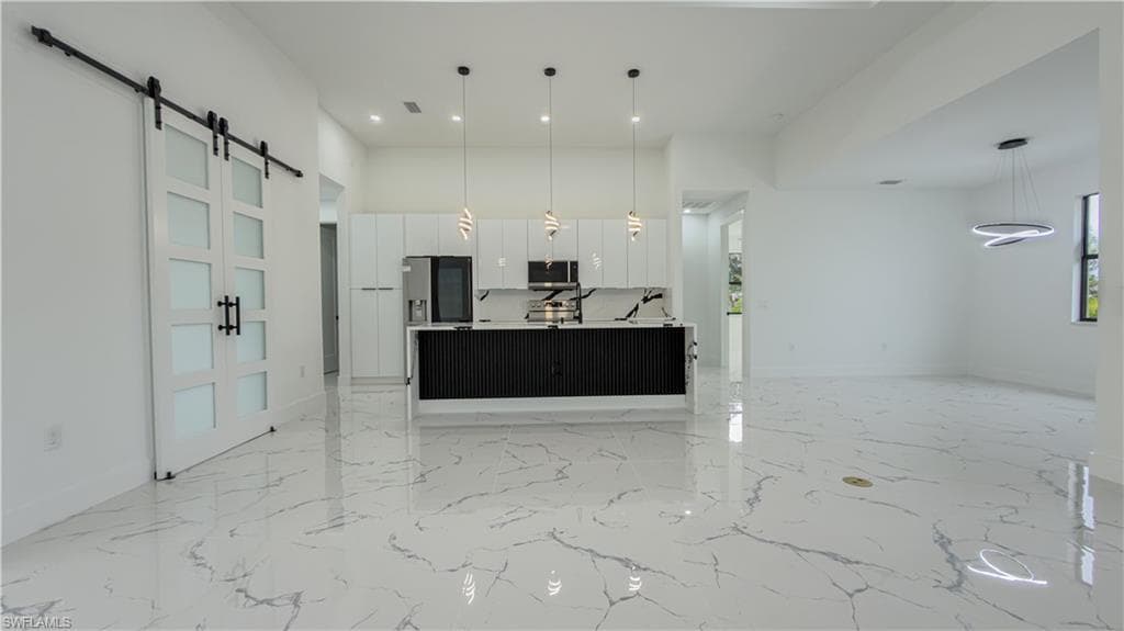 Unfurnished living room with a barn door, a towering ceiling, light marble finish flooring, and recessed lighting