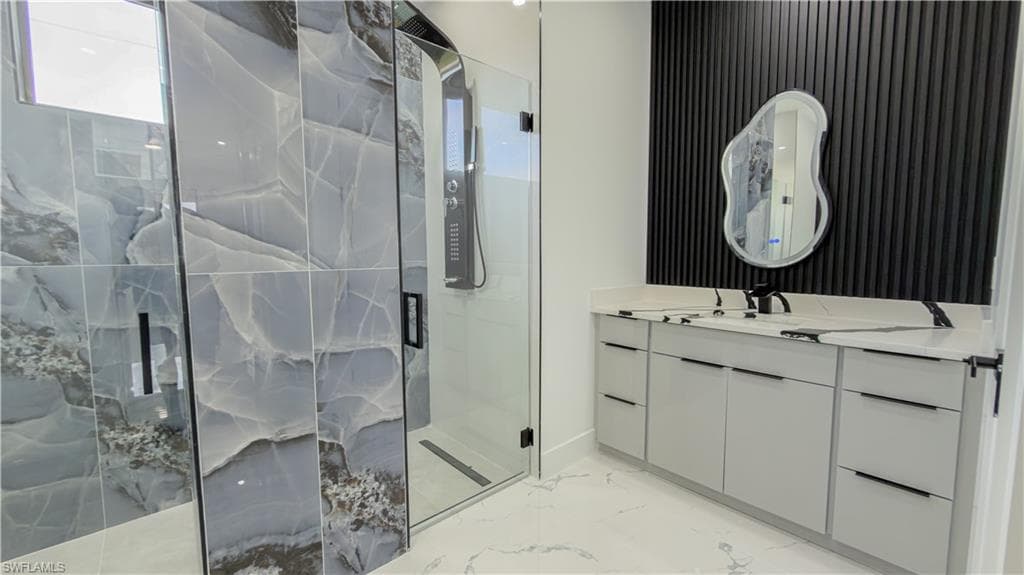 Bathroom with vanity, a marble finish shower, and light marble finish flooring