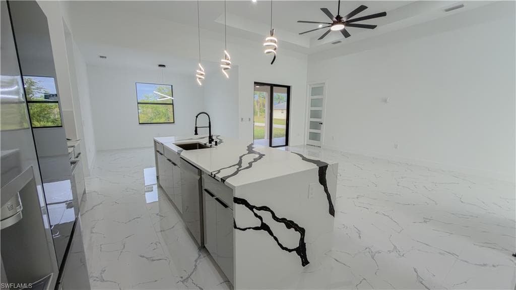 Kitchen with hanging light fixtures, light marble finish flooring, open floor plan, and modern cabinets
