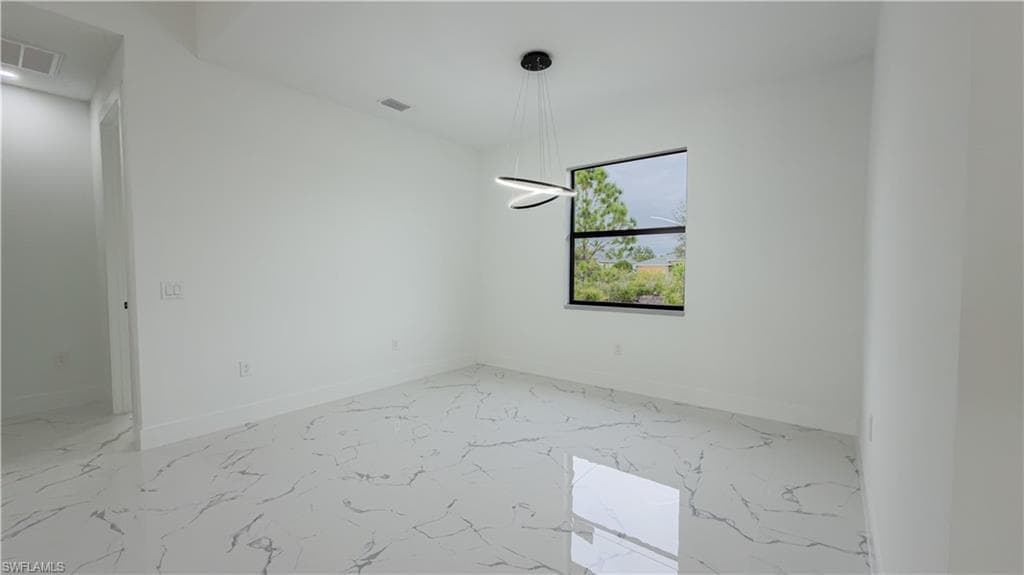 Spare room featuring light marble finish flooring and baseboards