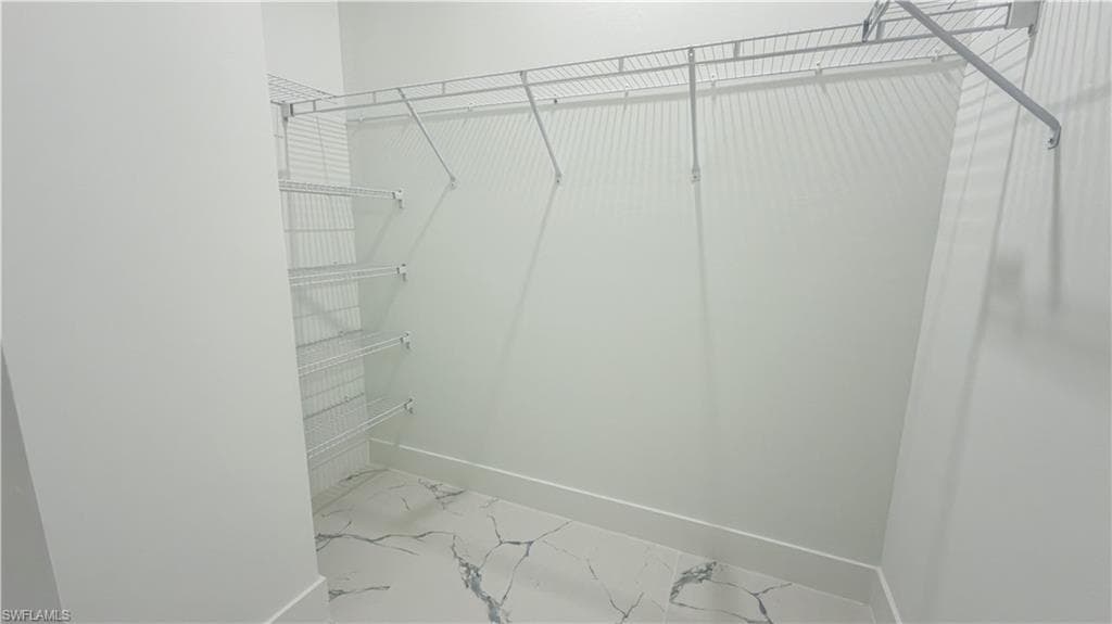 Spacious closet featuring light marble finish floors