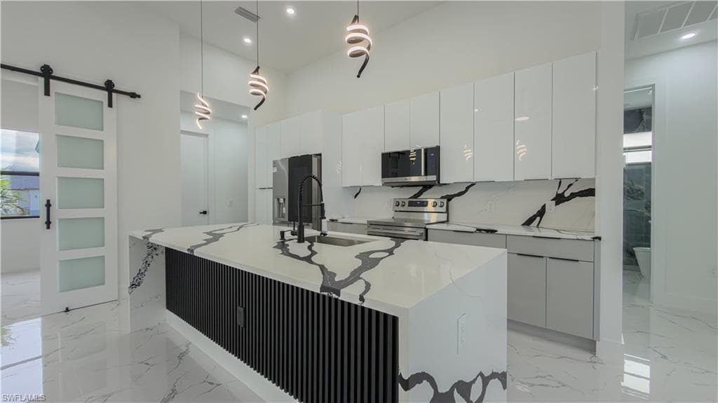 Kitchen with modern cabinets, a barn door, plenty of natural light, light stone counters, and recessed lighting