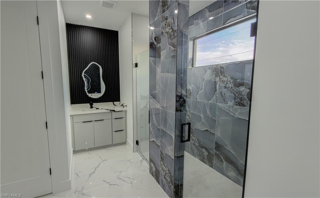 Bathroom with vanity, light marble finish flooring, a marble finish shower, and recessed lighting