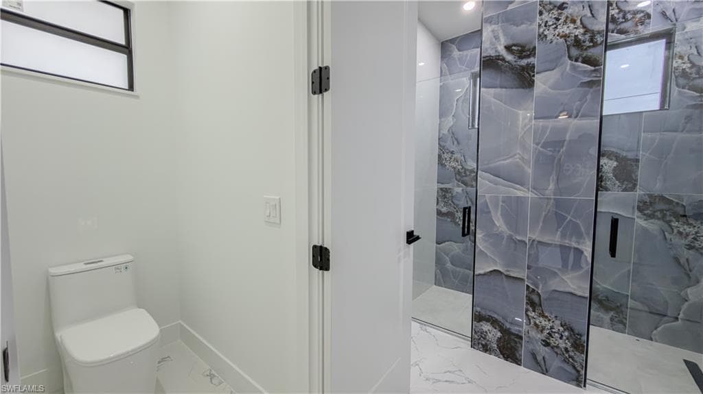 Bathroom featuring a marble finish shower and marble look tiles