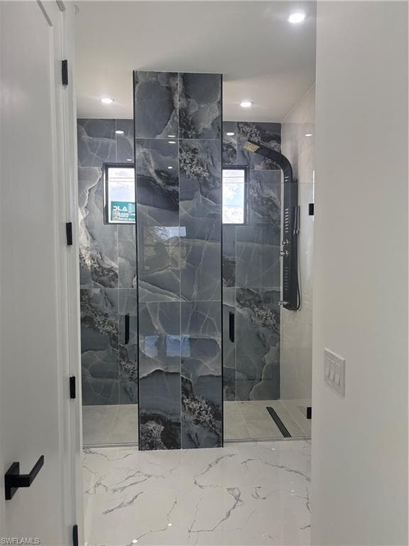 Bathroom with a marble finish shower and light marble finish flooring