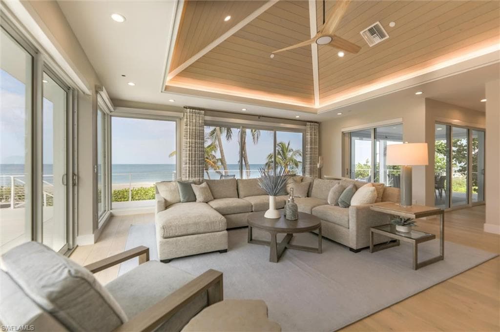 Living room with light hardwood / wood-style flooring, a tray ceiling, wooden ceiling, a water view, and ceiling fan