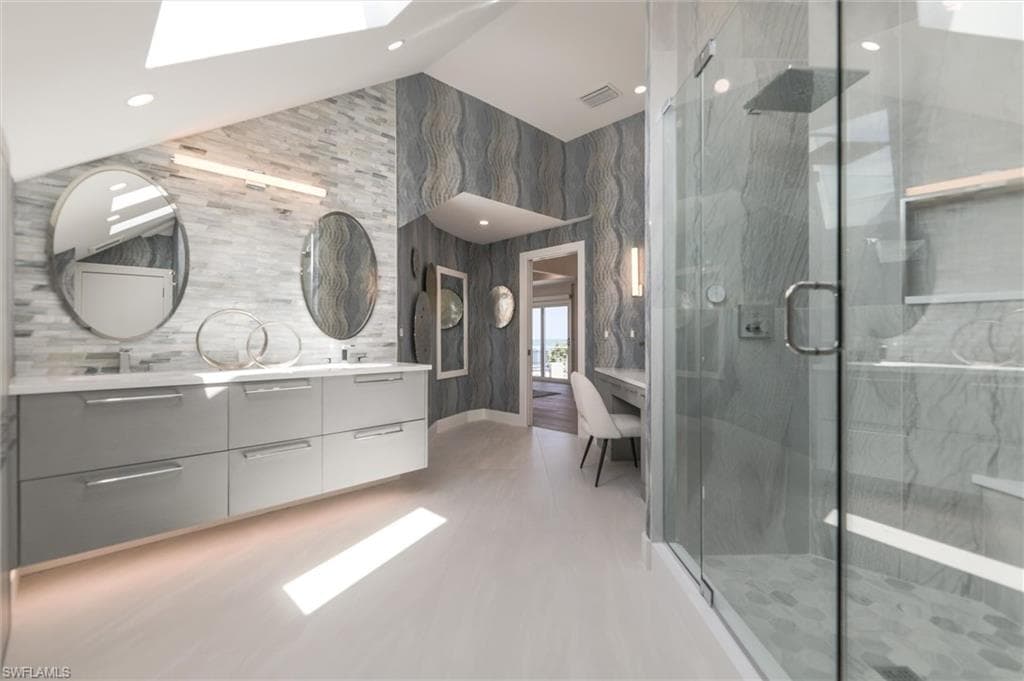 Bathroom featuring walk in shower, tile walls, a skylight, and large vanity