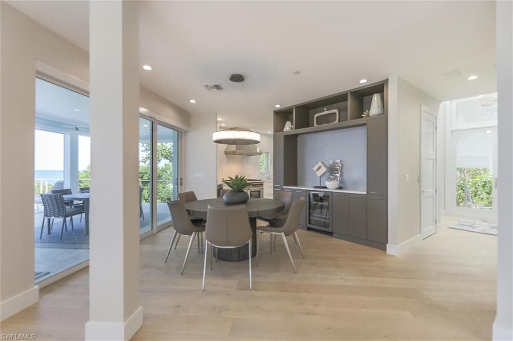 Dining space with wine cooler and light wood-type flooring