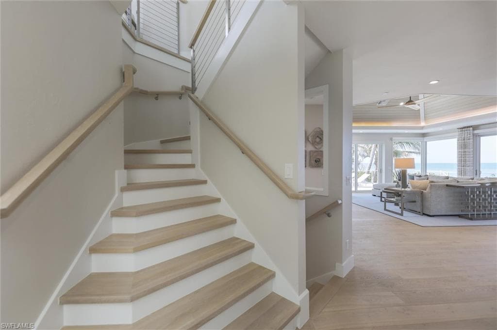 Stairs featuring hardwood / wood-style floors and a raised ceiling