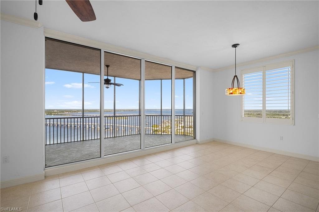 Spare room featuring light tile patterned flooring, ornamental molding, ceiling fan, and a water view